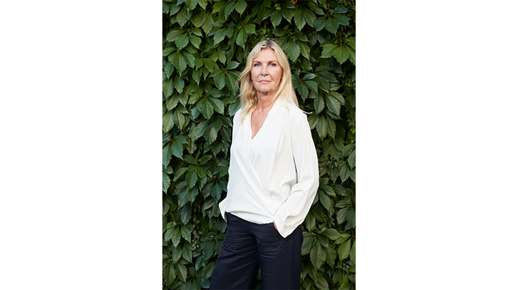 portrait of Dorte Mandrup in front of green leaves. 